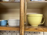 Side view shelf showing a small blue carafe, white casserole dish, and yellow nesting bowl