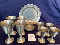 Photo showing all 4 pewter goblets, 4 pewter wine glasses, Leonard candy dish and International pewter tray together on blue cloth background.