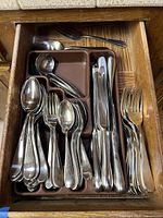 Drawer organizer with assorted forks, spoons, and knives separated in sections showing quantity and shape of flatware