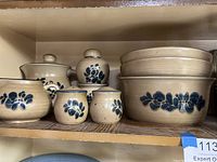 Stoneware kitchen items showing matching pieces with blue floral pattern: pitcher, salt and pepper shakers, creamer, sugar set, and smaller bowls.
