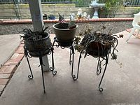 Wide photo showing all three pots each on their metal stands with trailing succulents inside the pots