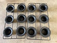 Top-down view showing two vintage black steel popover pans each containing six cups on a metal frame.