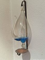 Full view of the vintage glass barometer mounted on metal bracket showing teardrop shape and blue liquid inside.