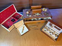 Overview of multiple boxes containing tie clips, collar attachments, cufflinks and tie tacs on wooden table