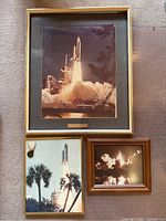 Three framed photos of NASA Shuttle launches, largest has a brass plaque