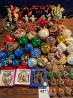 Wide view of vintage Christmas ornaments including glass balls, angels, musical themed pieces, and boxed ornaments on wooden surface against blue backdrop.