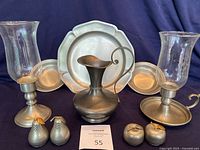 Full lot photo showing all items: 2 candle holders with etched glass hurricanes, metallic tray, pitcher with curled handle, 2 salt and pepper sets in fruit shapes, 2 pewter bowls
