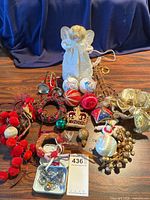 Vintage porcelain angel tree topper in white lace and assorted vintage Christmas ornaments including brass trumpets, baubles, garlands, bows, and hooks.