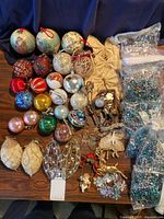 Full lot view showing various vintage Christmas ball ornaments, fabric ornaments, shaped metal and glitter ornaments, and multiple bags of beaded garland.