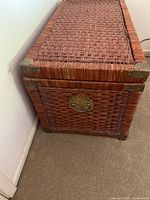 Side close-up of wicker chest showing woven pattern and metal corner protector