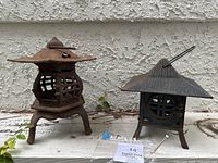 Both Asian cast iron garden lanterns side by side: one Mountain Cabin style with one broken leg, the other three-legged Pagoda style lantern.