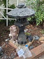 Front view of the black Dragon Foot Pagoda, pink Singha lion, and koi fish on a triangular pebble base, showing the pagoda top piece detached.