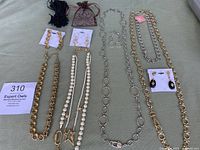 Top-down view showing all necklaces and earrings laid out on green fabric, some in pouches, emphasizing variety in styles and colors.