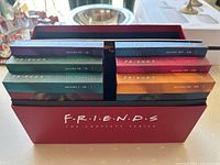 Red box containing six color-coded DVD volumes numbered with episode ranges.