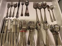 Full drawer view displaying all flatware pieces laid out including forks, spoons, knives, and serving utensils.
