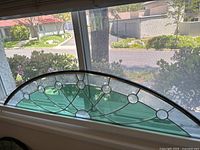 Full view of arch-shaped stained glass panel installed in window opening