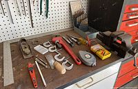 Overview of mounted vise, pipe wrench, drill bits, measuring tools and assorted hand tools on a workbench.