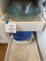 Photo of nested clear glass Pyrex bowls showing ribbed pattern, arranged by size inside a kitchen drawer.