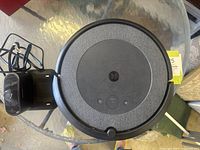 Top view of Roomba 13 vacuum with charging base showing circular form and textured upper surface.