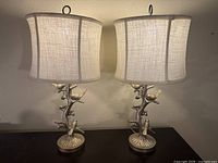 Both lamps illuminated on dark wood surface against a beige wall, front view