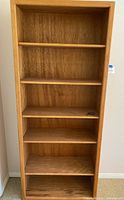Front view of wooden book shelf showing all 5 shelves, extra pegs on one shelf