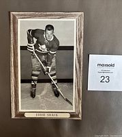 Front view of the framed black and white Eddie Shack hockey photo with nameplate and wood-grain frame.