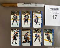 Front side photo showing 7 Edmonton Oilers mini keychains with player images including Paul Coffey, Kevin Lowe, and Grant Fuhr. Sharpie pen for scale.