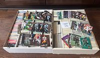 Two large open monster boxes containing stacked and loose 1990s NFL football cards, showing the quantity and organization of the lot