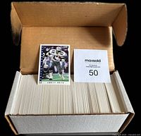Open top view of packed cards inside original box with a visible player card on top plus MaxSold lot tag.