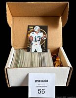 Box full of approximately 150 football cards from the 1996 Zenith NFL set with one card standing upright showing player in white Miami Dolphins uniform, number 13.