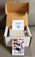 Open box showing the collection of folded football cards and a card featuring NFL player Drew Bledsoe standing outside the box.