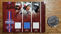 Front of the jersey card showing player portraits and game-worn jersey swatches for Andre Dawson, Gary Carter, and Tony Perez, alongside a Canadian quarter for scale.