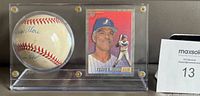 Signed baseball and card displayed together in Lucite stand, showing both autographs and card image
