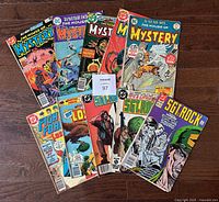 All 10 comic books spread on wooden surface showing titles and covers with noticeable wear from 1975-1991.