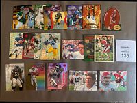 Top view of 20 NFL football insert cards laid out in two rows, showing a variety of star players and colorful holographic designs.