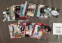 Photo showing a partial spread of autographed NHL hockey cards featuring multiple players including a goalie, a Vancouver Canucks player, and more.