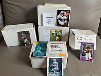 Photo showing five white boxes containing near complete NFL football card sets, with sample cards displayed on the boxes.