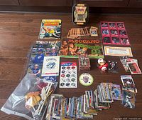 Entire lot laid out showing key items: comic, catalogue, postcards, Yu-Gi-Oh! tin, cards, toy parts, memorabilia