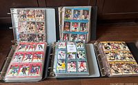 Five binders open displaying multiple nine-pocket pages filled with hockey cards