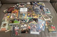 Pile of various rookie cards spread out on couch with some in top loaders