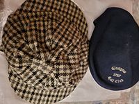 Brown and beige houndstooth patterned lambswool hat and navy blue Glasgow Golf Club golf cap side by side