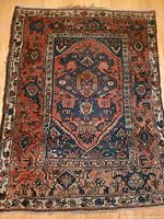 Full view of the antique hand knotted rug showing central medallion and border patterns with navy and rust red colors.