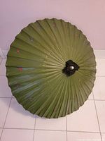 Top-down view of the opened green parasol showing the circular canopy and scattered small floral accents.