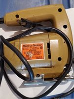 Photo of the Black & Decker jig saw showing the body with attached cord and label with safety information.
