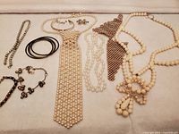 Overview of entire vintage costume jewelry collection including necklaces, bracelets, bangles, and earrings laid out on white background.