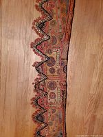 Full length view of the fabric showing embroidered patterns and tassel-trimmed scalloped edge.