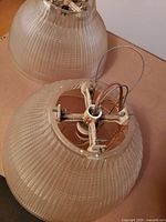 Two vintage Holophane lamps in crystal ribbed glass with mounting hardware visible inside, laid on a surface.