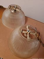 Two crystal glass lamp globes displayed side by side with metal mounting fittings and wiring visible