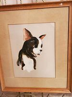 Framed vintage oil painting of a black and white dog with large ears, mounted on satin then board, showing wear consistent with age.
