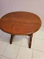 Oval pine wood fold-leaf table with surface wear and age marks, shown unfolded.